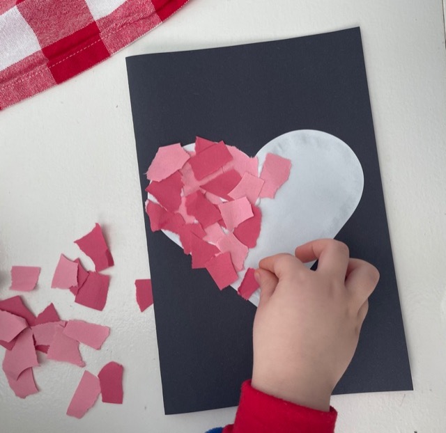 Three year old making torn paper heart for valentine