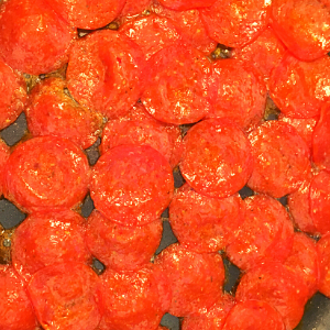 Closeup of pepperoni frying in skillet