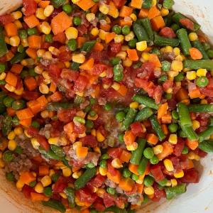 Adding in mixed vegetables to browned beef mixture